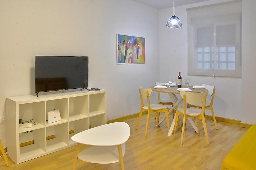 sala de estar con mesa, sillas y TV en Exclusivo Apartamento en el Centro de Sevilla, en Sevilla