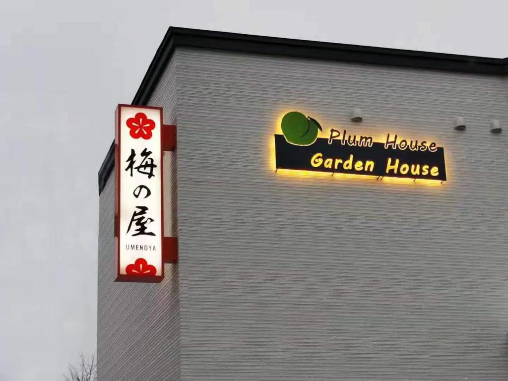 un edificio con un letrero para una casa en el jardín en Plum House Otaru, en Otaru