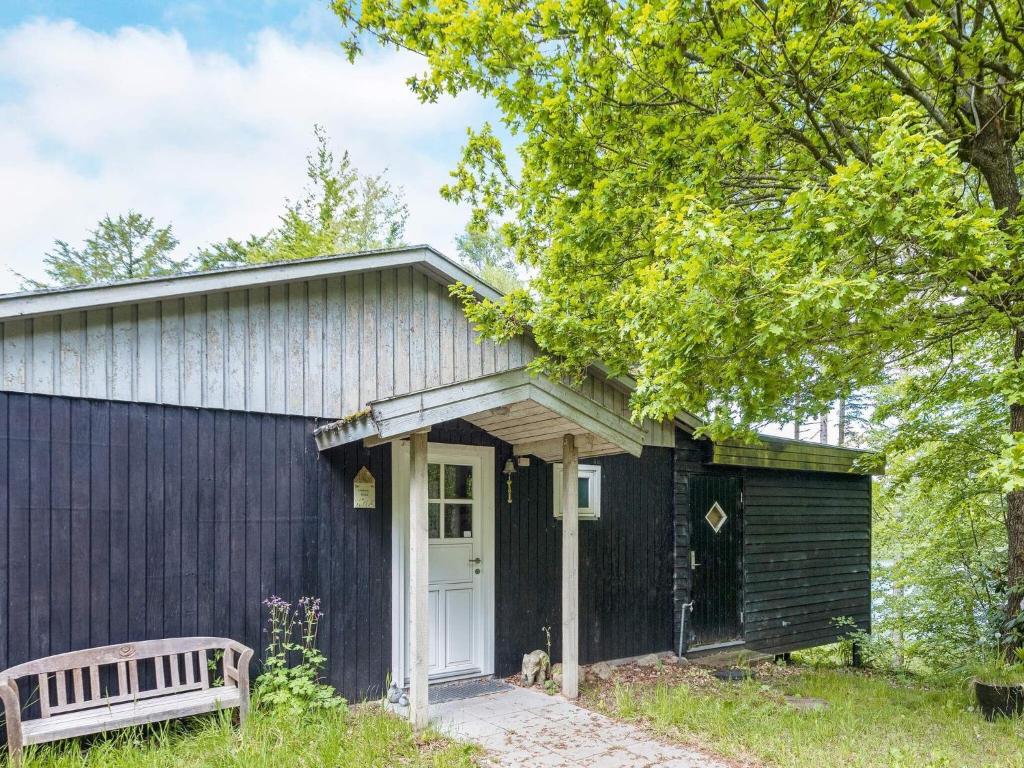 una casa negra con un banco delante en Holiday home Aars II, en Års