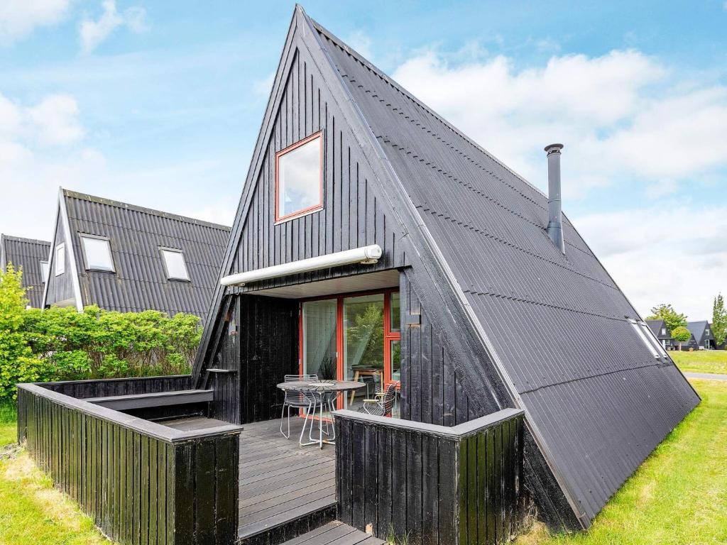 a black house with a black roof and a deck at Holiday home Farsø XXIII in Farsø