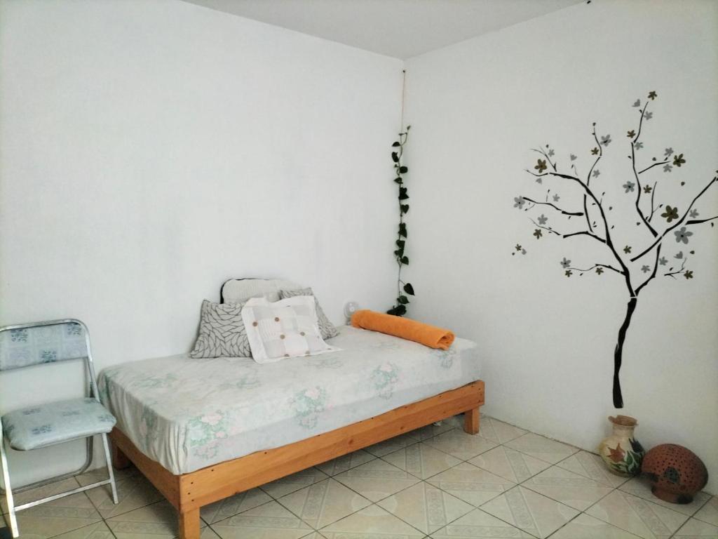 een slaapkamer met een bed en een boom aan de muur bij Casa Brenamiel in Santa María Azompa
