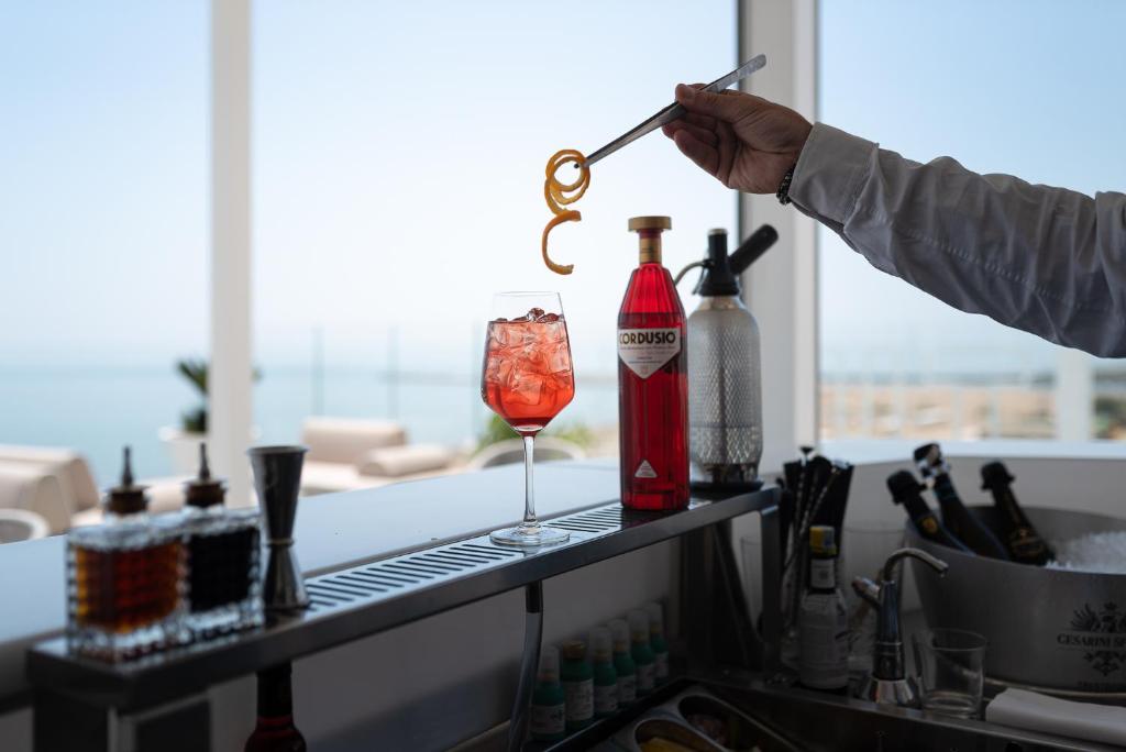 a person is pouring a drink into a glass at Unico Hotel Caorle in Caorle
