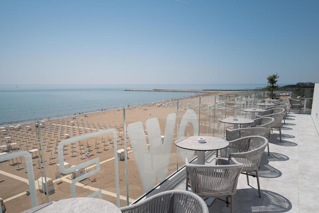 a row of tables and chairs next to a beach at Unico Hotel Caorle in Caorle