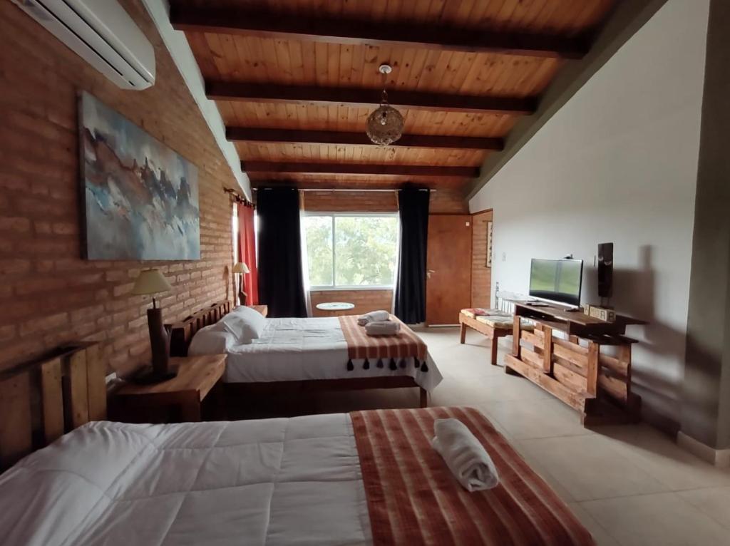 Cette chambre comprend deux lits et une télévision. dans l'établissement Hostería La María, à Rosario de la Frontera