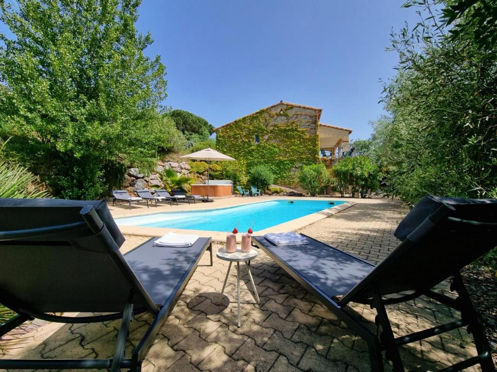 dwa krzesła i stół obok basenu w obiekcie Le Jardin des Olives w mieście Caunes-Minervois