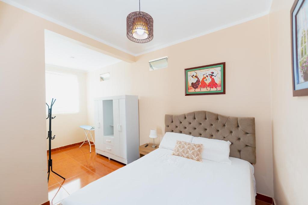ein weißes Schlafzimmer mit einem großen Bett und einer Lampe in der Unterkunft Edificio Rojo Departamentos. in Tarapoto