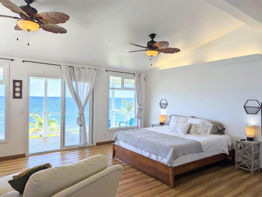 a bedroom with a bed and a balcony with the ocean at Maka'Ala Lani - A view of Heaven in Keaau