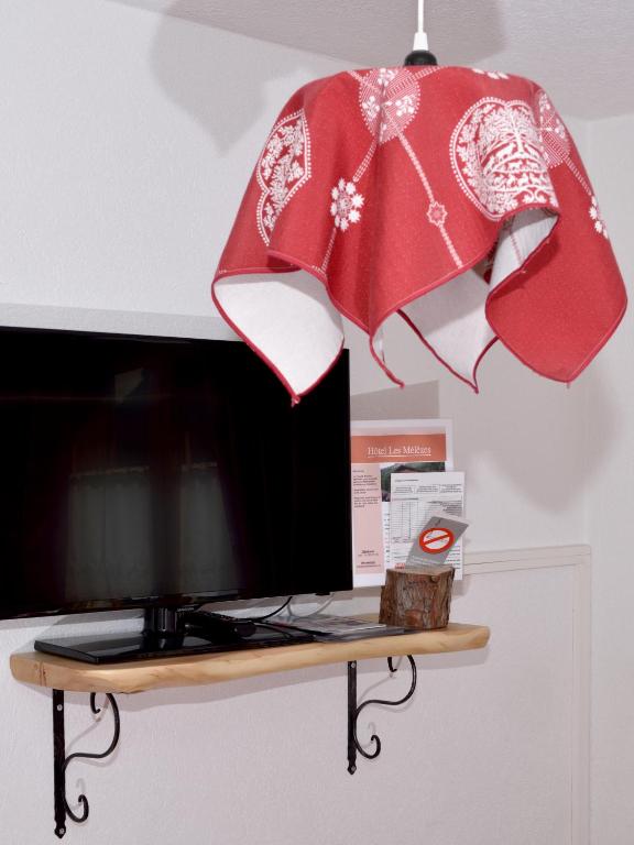 a red cloth is hanging above a television at Hotel Les Mélèzes in Haudères