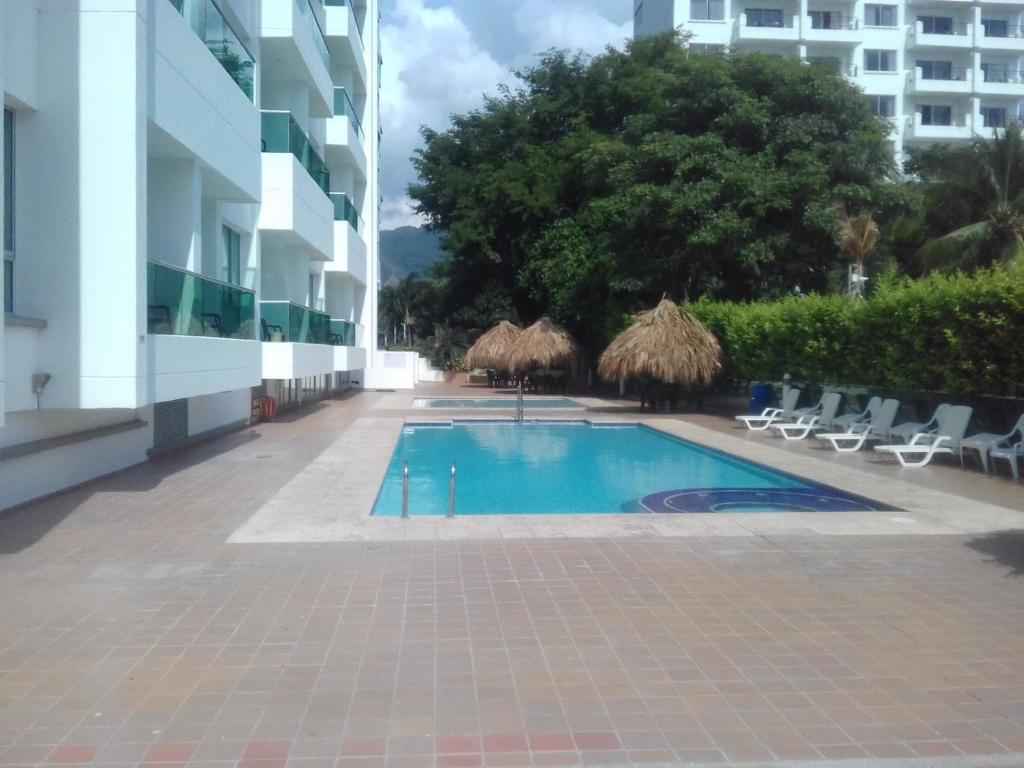 a swimming pool with chairs and umbrellas next to a building at Costa Azul Apto603 in Playa Dormida
