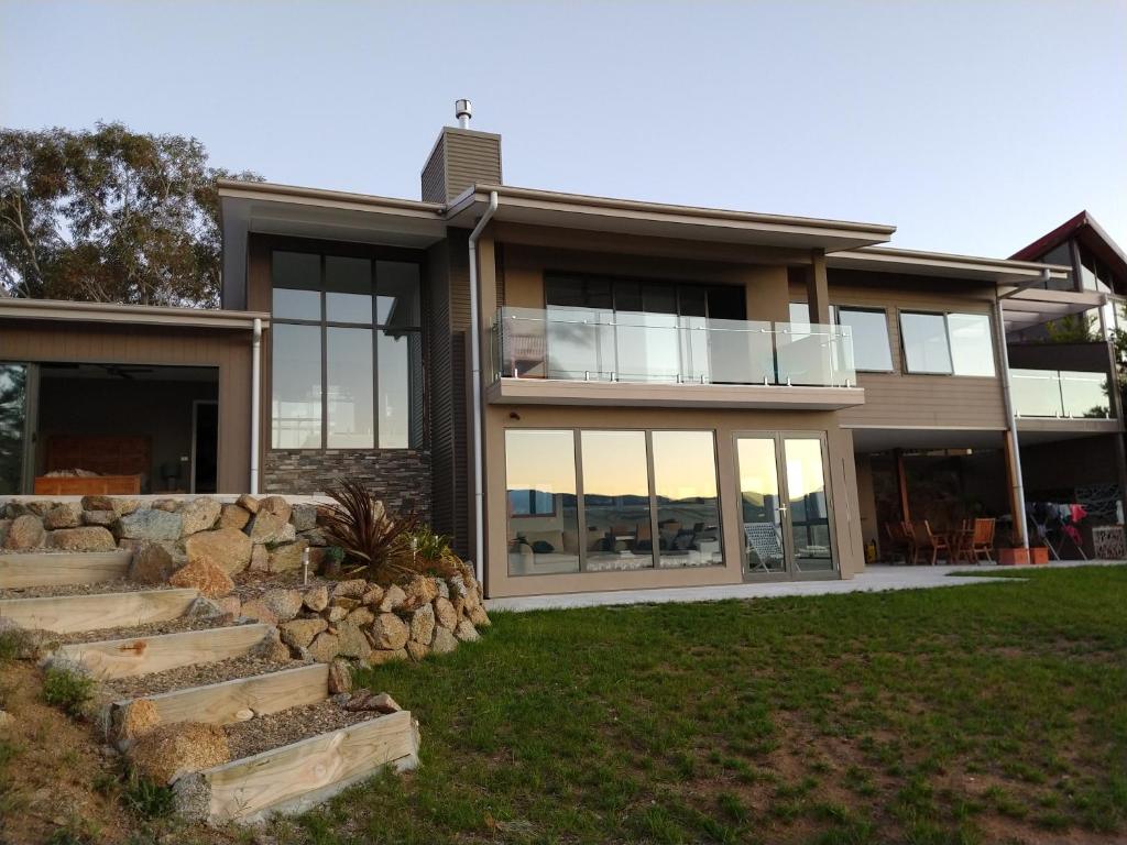 a house with large windows and a stone wall at Willow Bay Lodge in Jindabyne