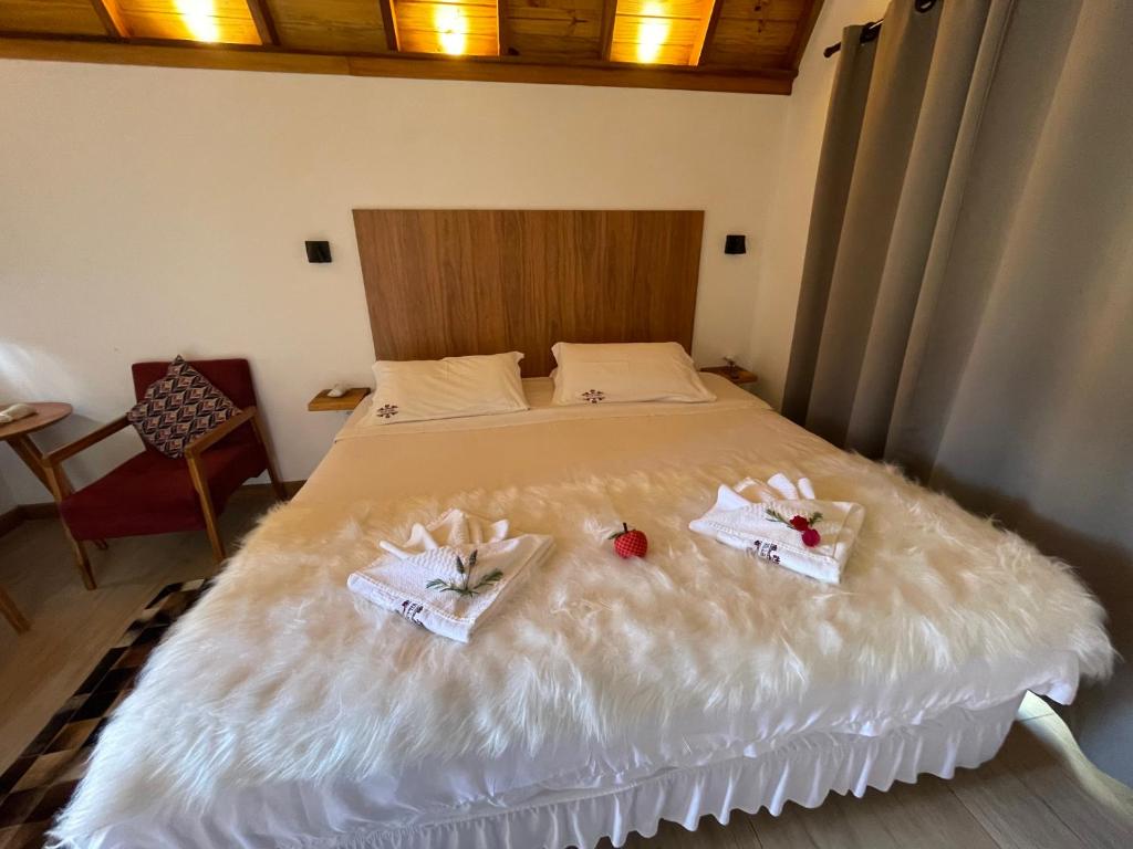 a bedroom with a large white bed with two towels on it at VILLA ITÁLIA CHALÉ in Santo Antônio do Pinhal