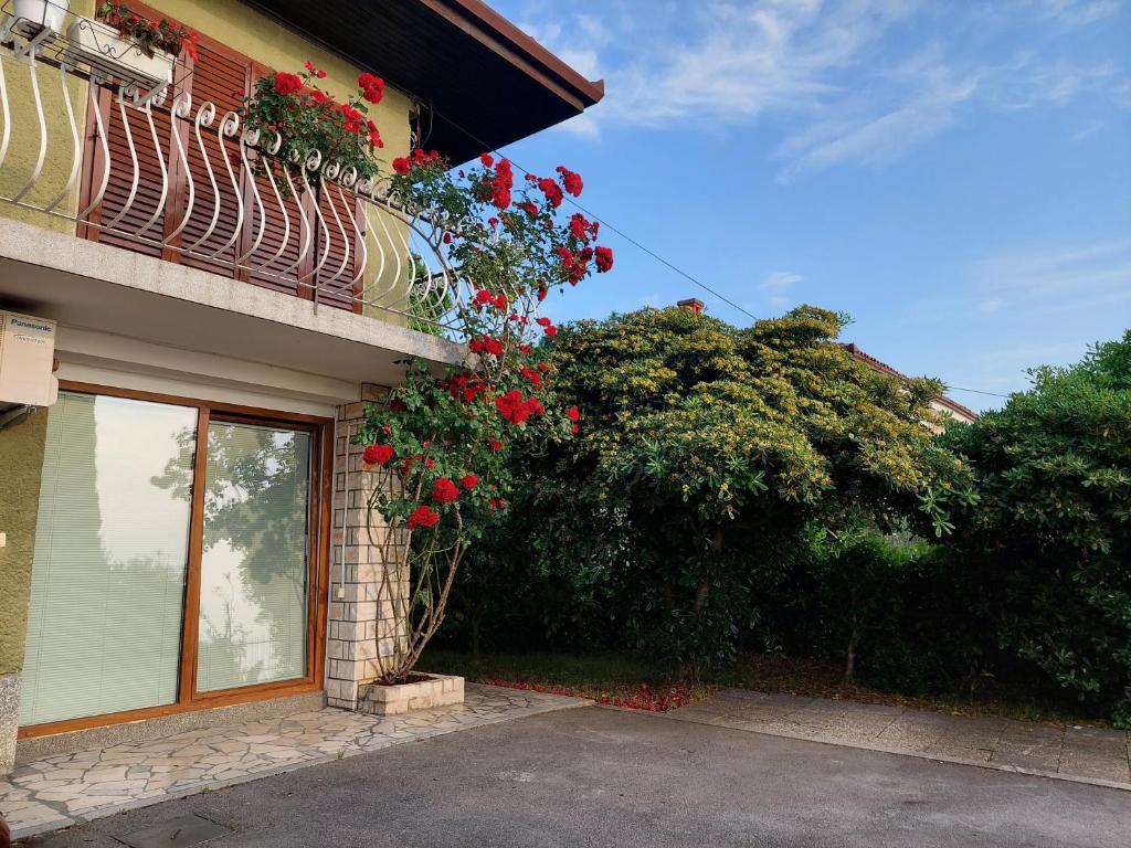 a building with a balcony with red flowers on it at Apartma Niko in Piran