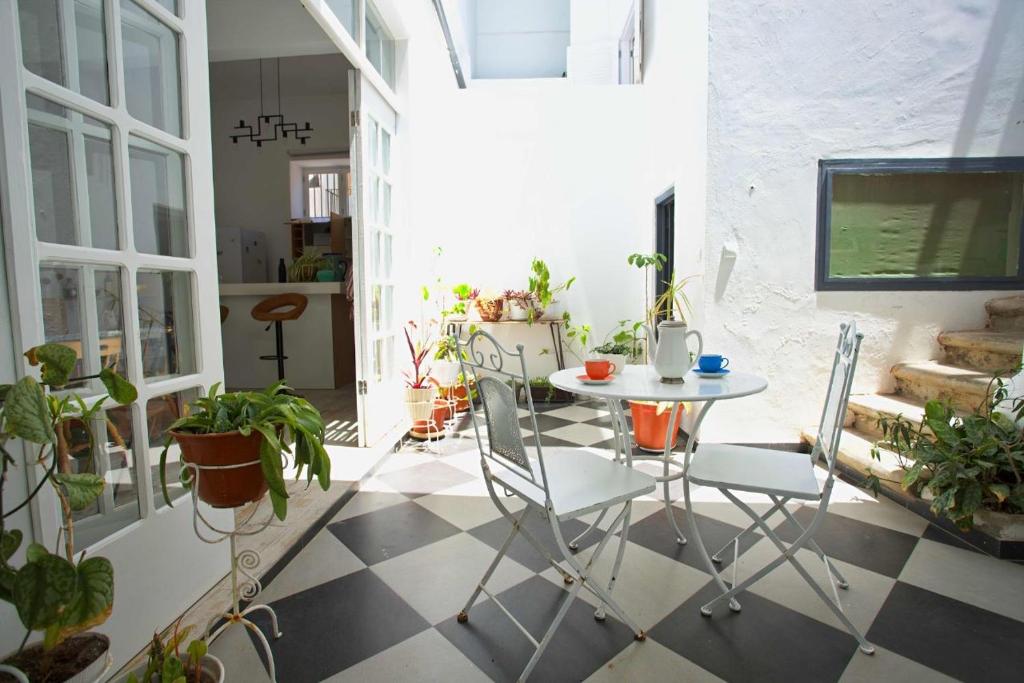 a patio with a table and chairs and plants at As Hortênsias in Mindelo