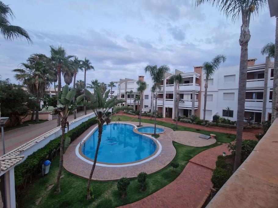 une piscine bordée de palmiers et un bâtiment dans l'établissement Plage, Piscine, et Confort Moderne, à Skhirat