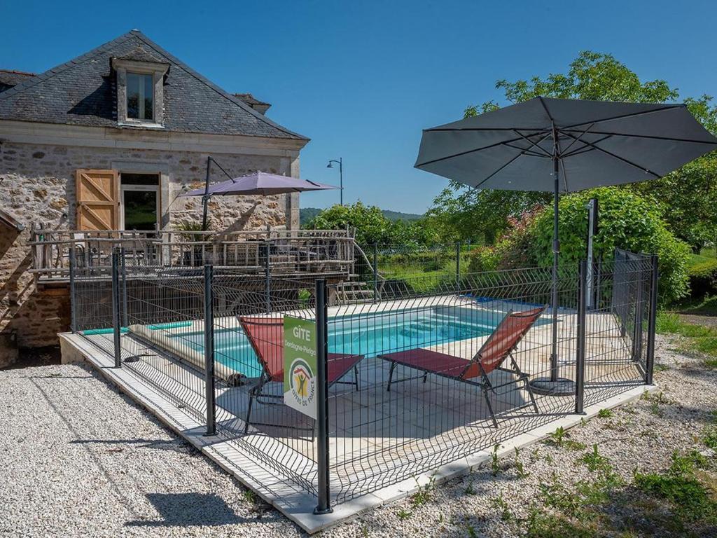 een kooi met een zwembad en 2 stoelen en een parasol bij Gîte Terrasson-Lavilledieu, 3 pièces, 4 personnes - FR-1-616-263 in Terrasson