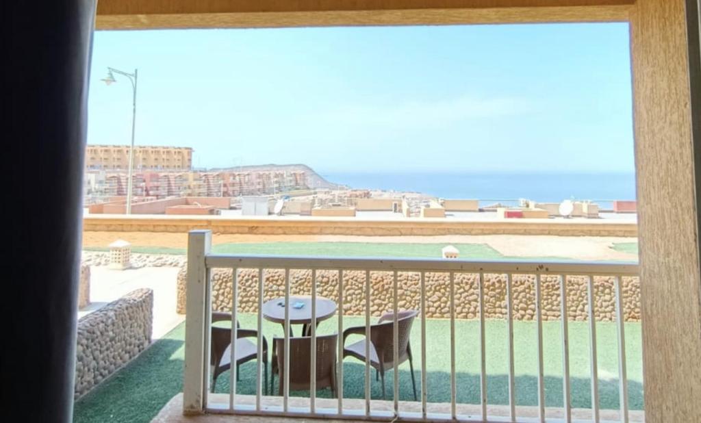 balcone con tavolo, sedie e vista sull'oceano di الحدائق المعلقة المصطبة الخامسة الهانجينج شاليه 9 للعائلات فقط a Ain Sokhna