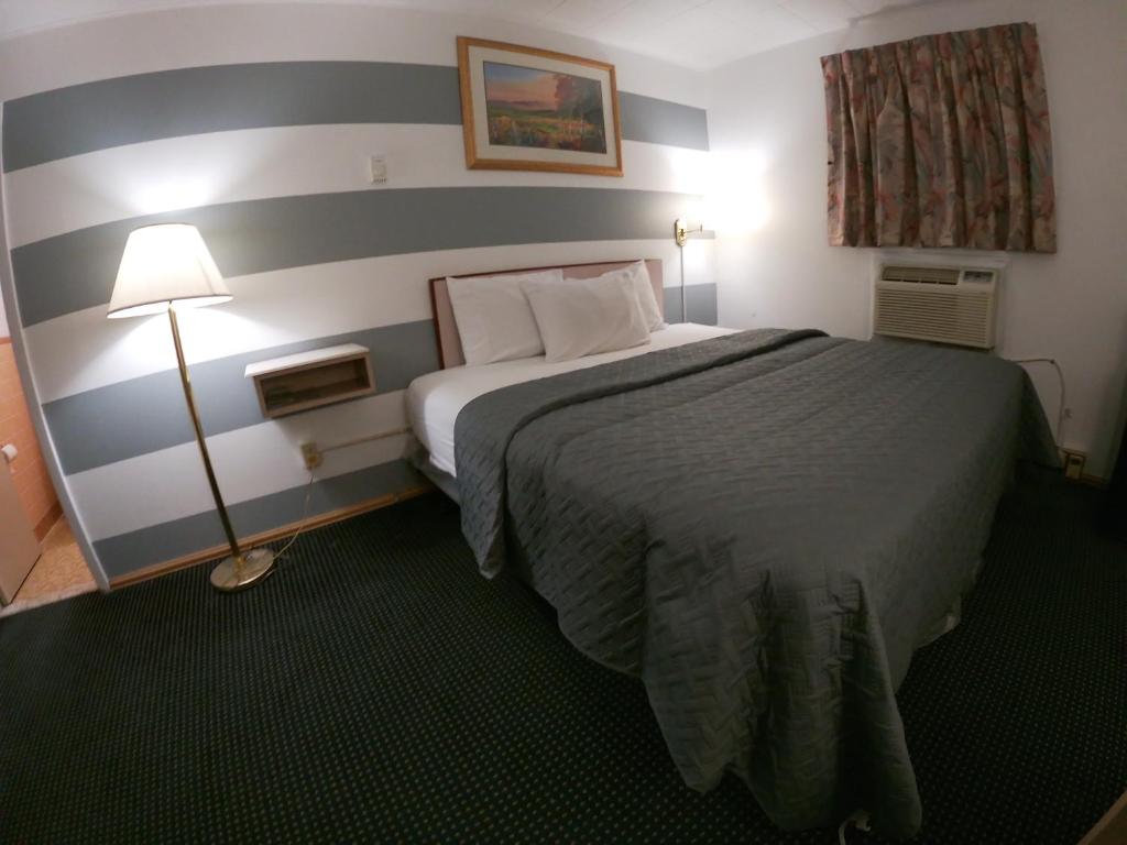 une chambre d'hôtel avec un lit et un mur rayé dans l'établissement Budget Inn Clearfield PA, à Clearfield