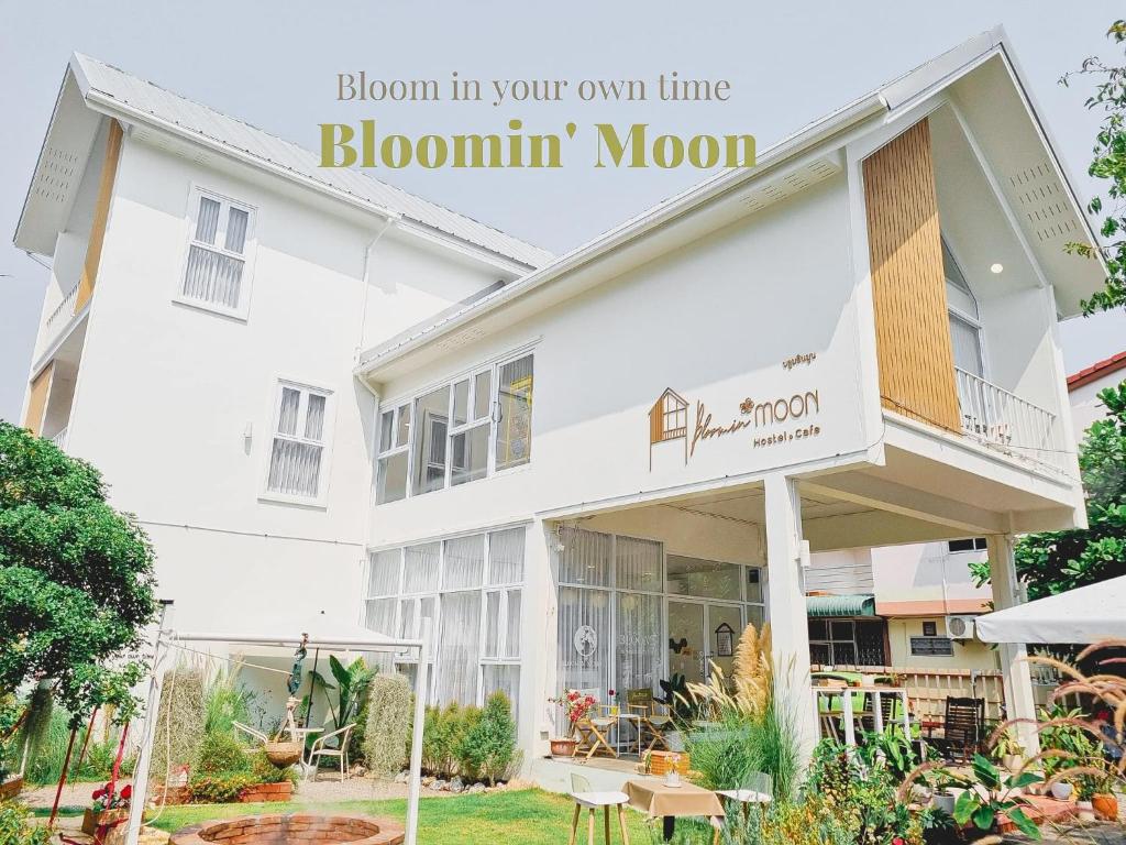 un edificio blanco con una señal que lee florecer en tu propio tiempo. en Bloomin' Moon hostel & cafe, Chiang Mai Old Town, en Chiang Mai