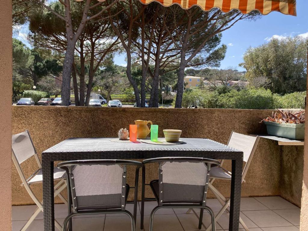 - une table et des chaises sur une terrasse avec un parasol dans l'établissement Appartement 2P avec Mezzanine, Balcon, Parking Privé - À 200m de la Plage de la Nartelle - FR-1-226-523, à Sainte-Maxime