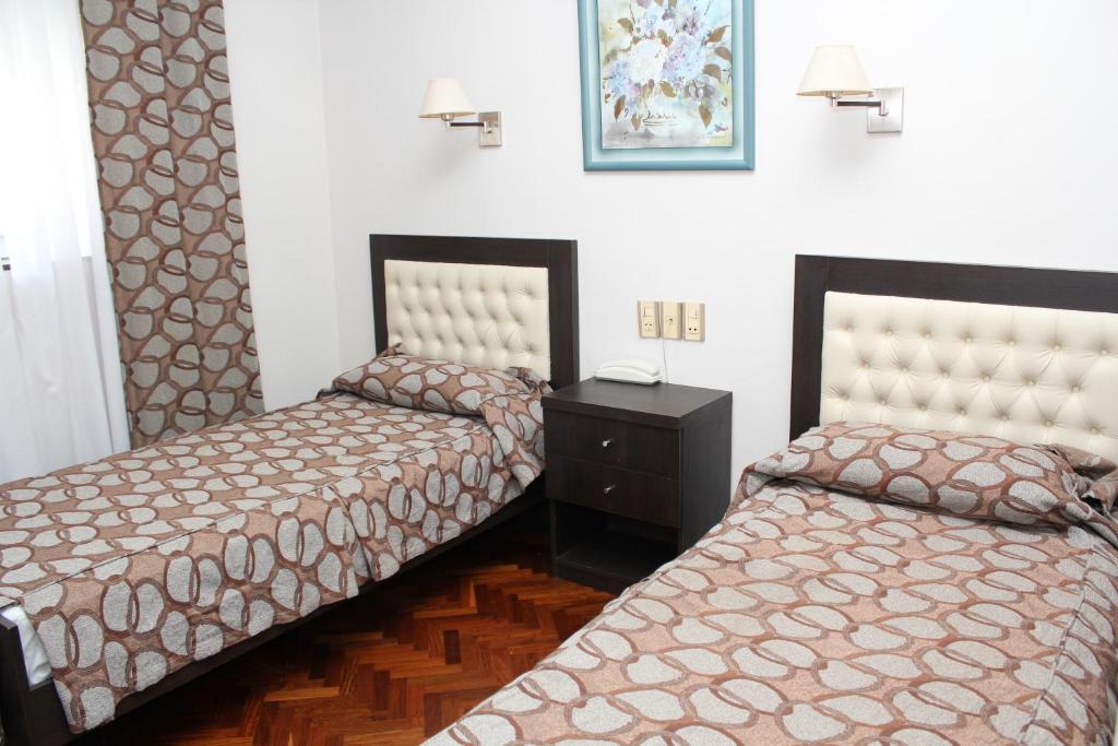 Ayacucho Palace Hotel في بوينس آيرس: غرفة بسريرين وخزانة