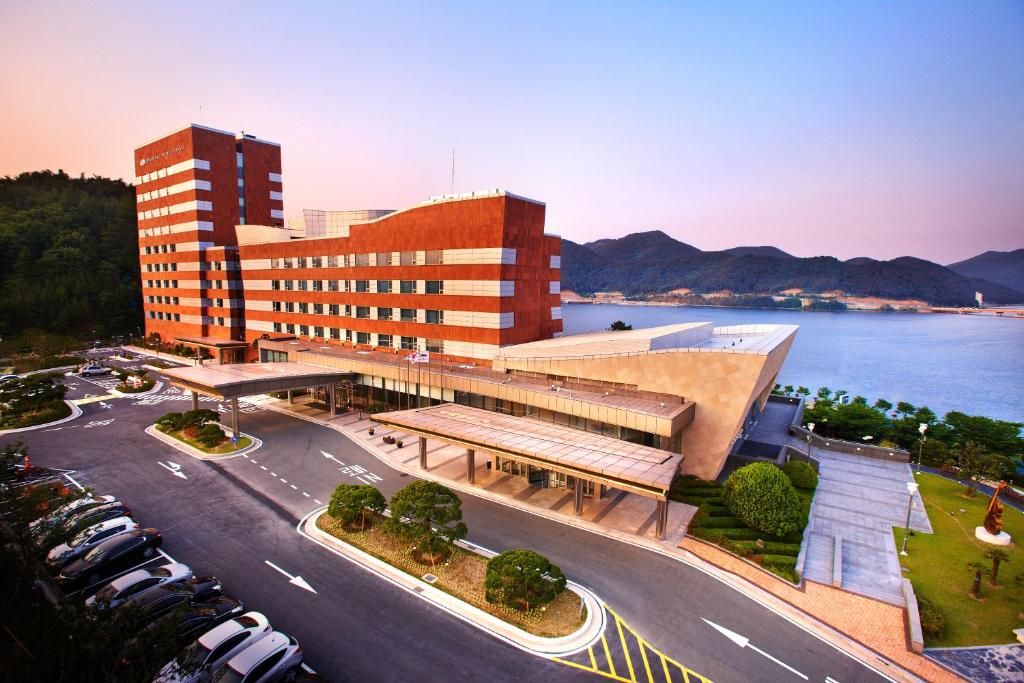 a building with a parking lot in front of a street at Geoje Samsung Hotel in Geoje 
