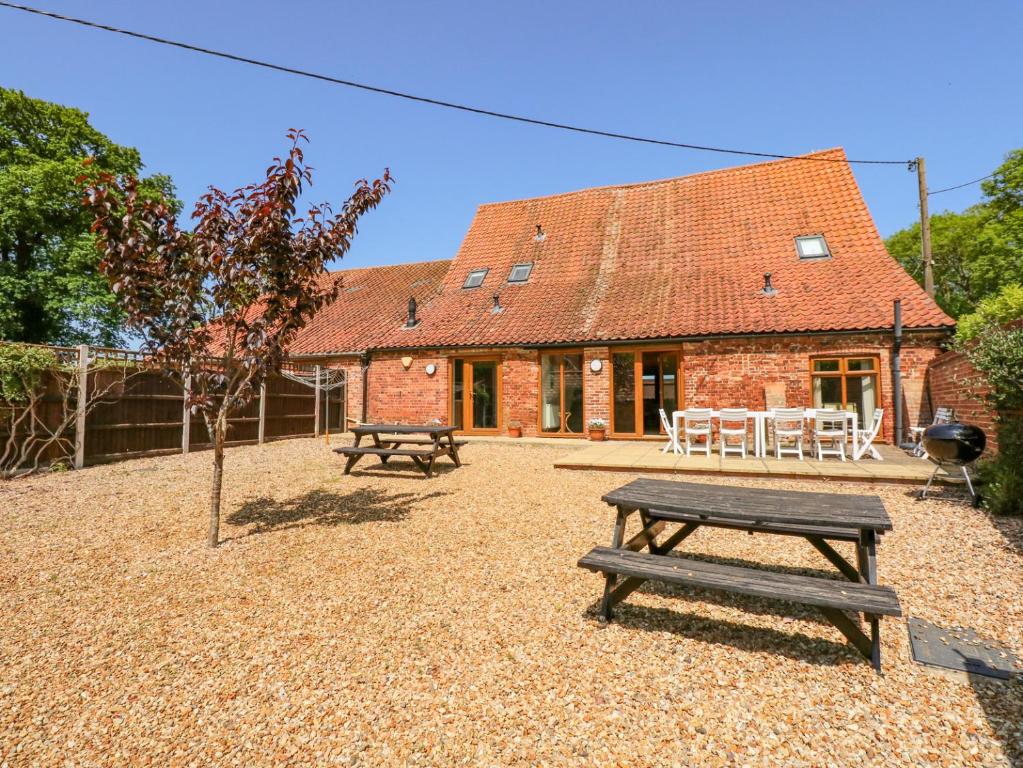 a house with two picnic tables and a building at Hadleigh Farm Barn in Gayton