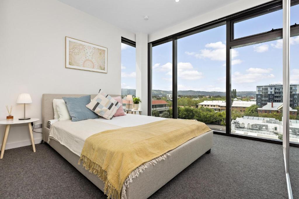 a bedroom with a bed and a large window at Ambrosia - East End Hillside Haven in Adelaide