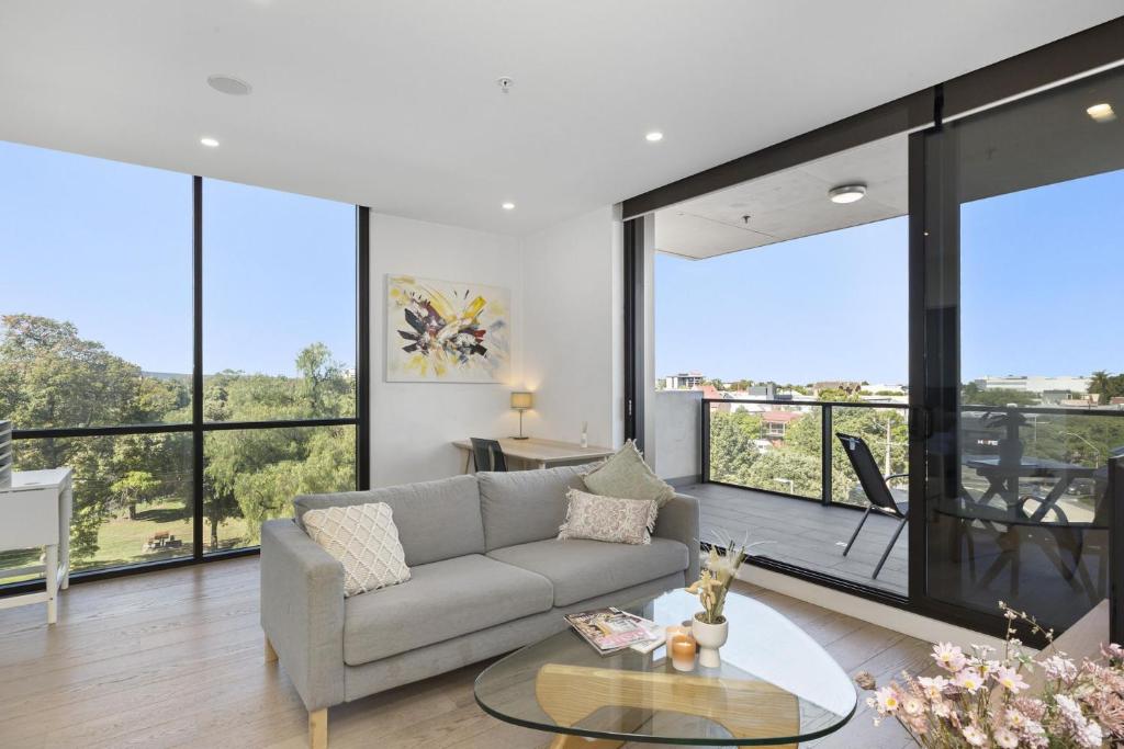 a living room with a couch and large windows at Oleria - Serene Bohem Retreat in Adelaide