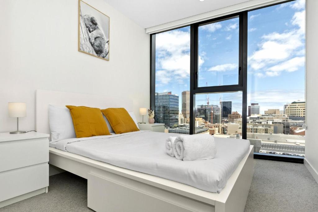 1 dormitorio con cama blanca y ventana grande en Iris - The Skylight Escape Apartment, en Adelaida