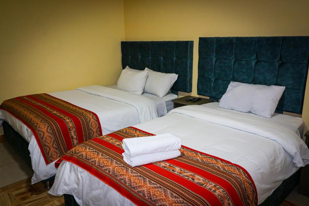 duas camas num quarto de hotel com toalhas em Cusco Hawka Pacha hostal em Cusco