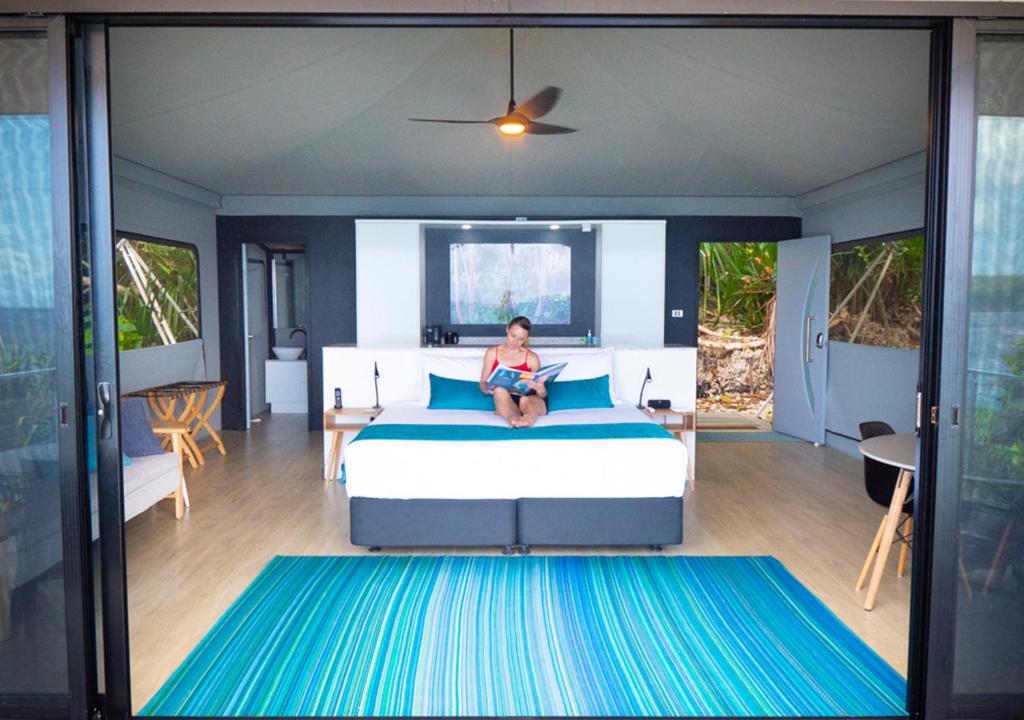 Eine Frau, die in einem Schlafzimmer auf einem Bett sitzt. in der Unterkunft Swell Lodge in Flying Fish Cove