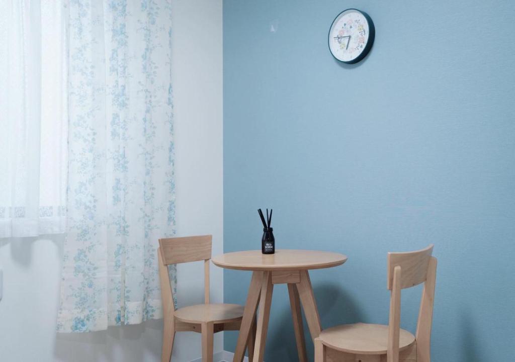 a table and two chairs and a clock on a blue wall at ookubo! 大久保! 新宿步行距离! 精品新装公寓! 大久保车站步行7分钟! 干湿分离! 智能马桶! 高速无限制网路 201 in Tokyo