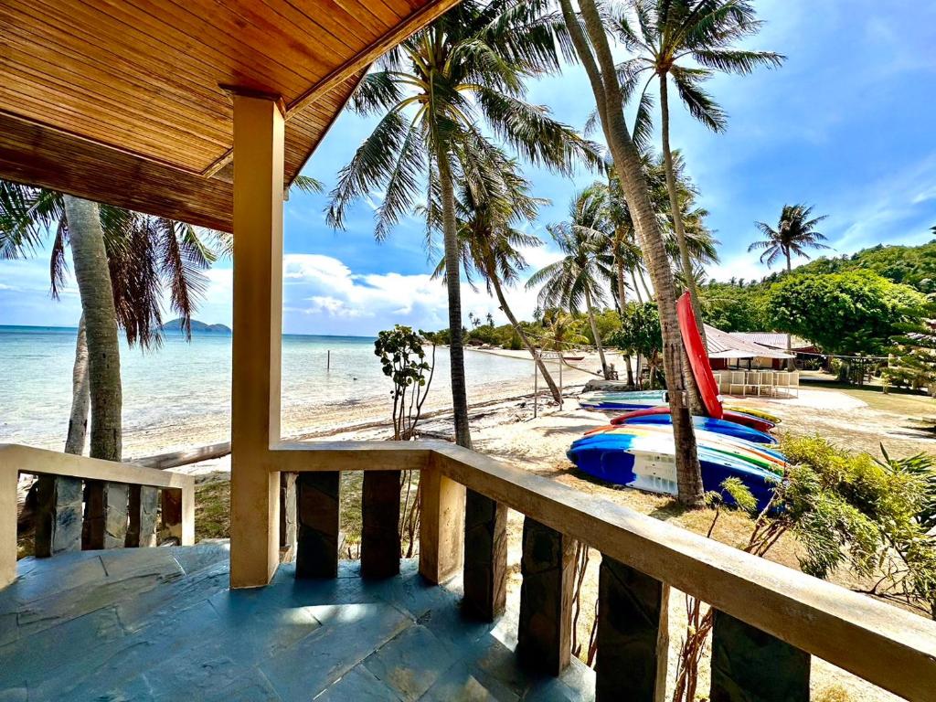 a balcony of a resort with a beach with a surfboard at Beck's Resort in Haad Pleayleam
