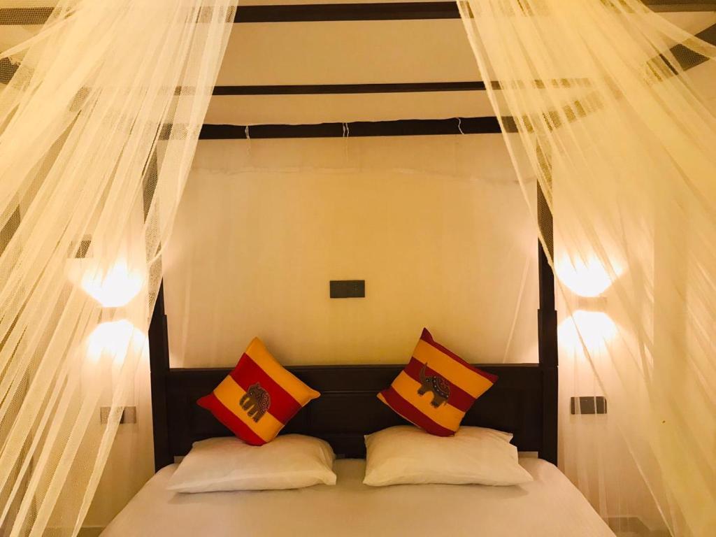 a bed with white curtains and pillows on it at LSC Villa in Weligama