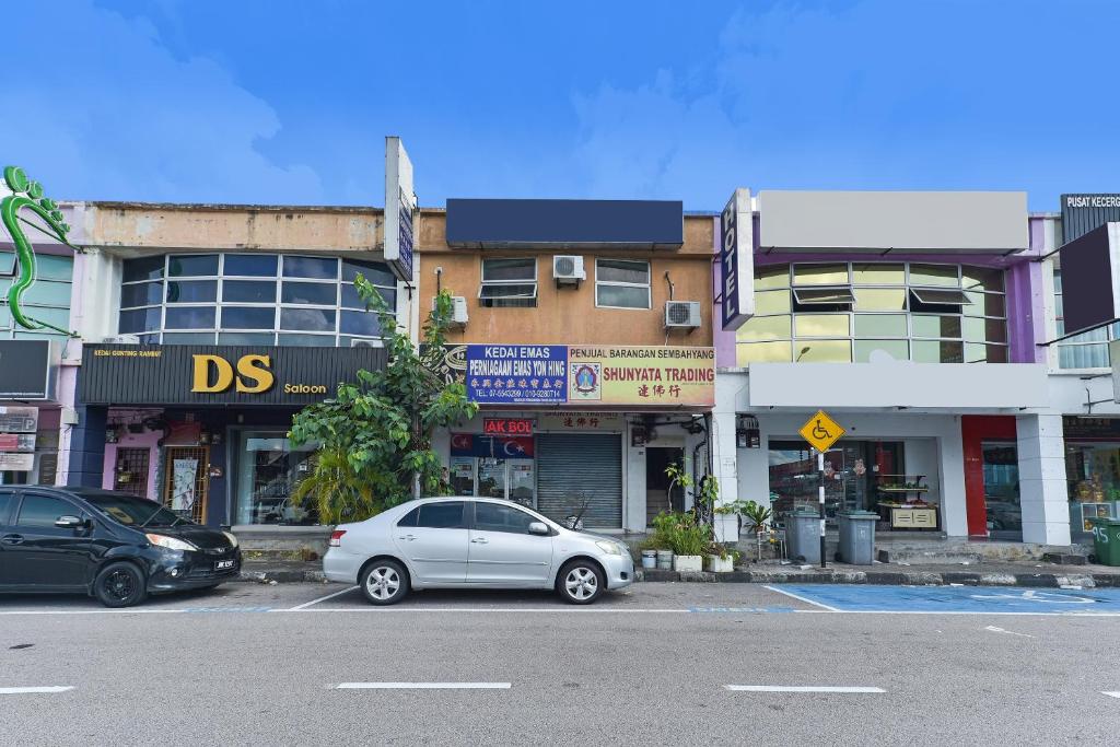 a white car parked in a parking lot in front of buildings at OYO 90794 Maple Hotel in Skudai