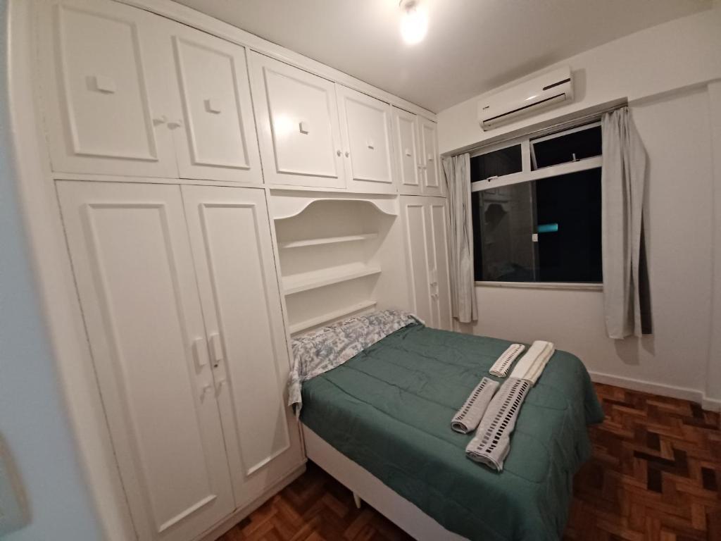 a small bedroom with white cabinets and a bed at Apartamento Jardim Botânico in Rio de Janeiro
