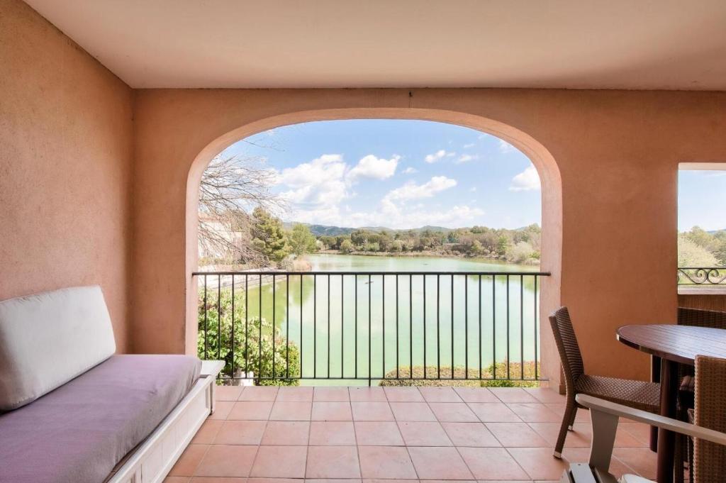 een kamer met een balkon met uitzicht op een meer bij Village Pont Royal en Provence - maeva Home - Appartement 2 pièces 4 person 154 in Mallemort