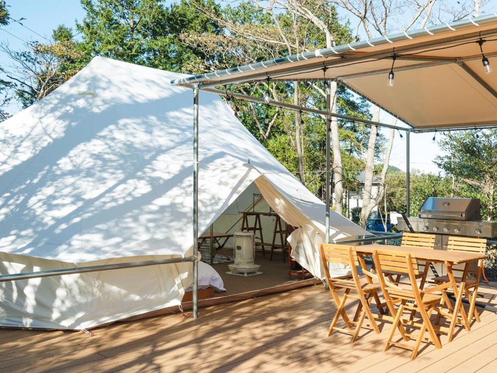 a tent with chairs and a table on a deck at K‘ｓCAMP伊豆高原　グランピング in Futo