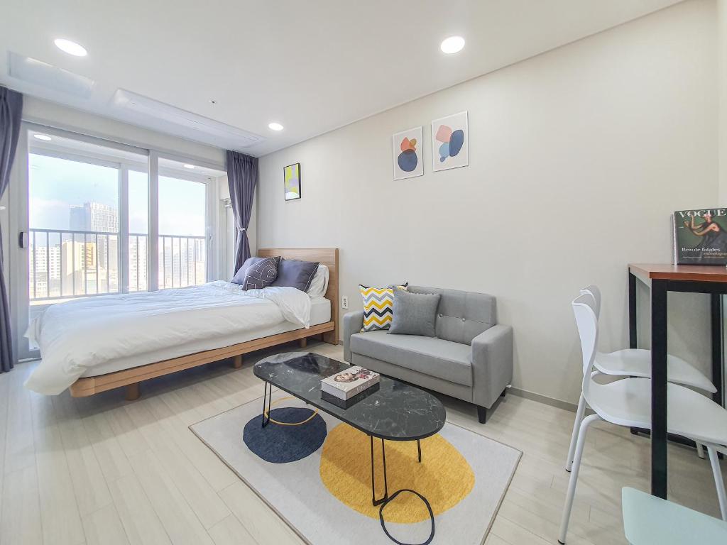 a bedroom with a bed and a couch and a table at Jeju Centerpoint N Residence in Jeju