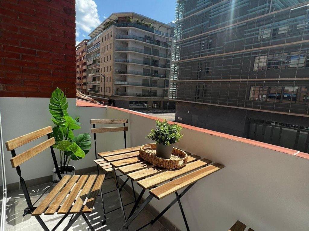drewniany stół i krzesła na balkonie z budynkami w obiekcie Holidays2Malaga Lebrija 3 bedroom & Terrace & Parking & Smart TV w Maladze