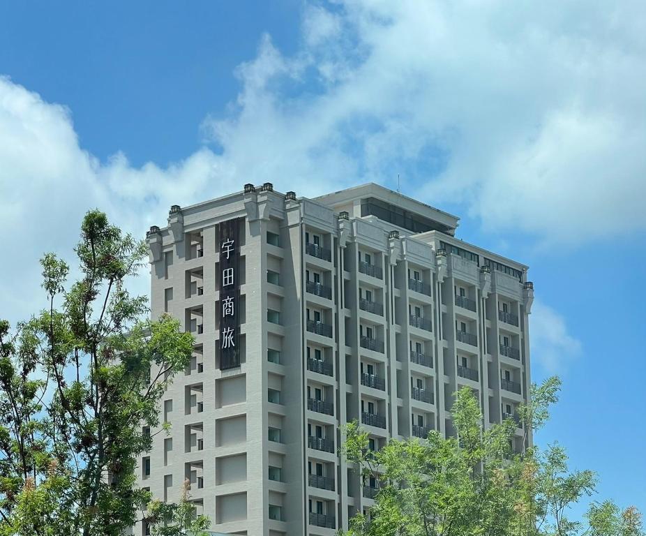a tall gray building with trees in the foreground at E Hotel in Xinshi