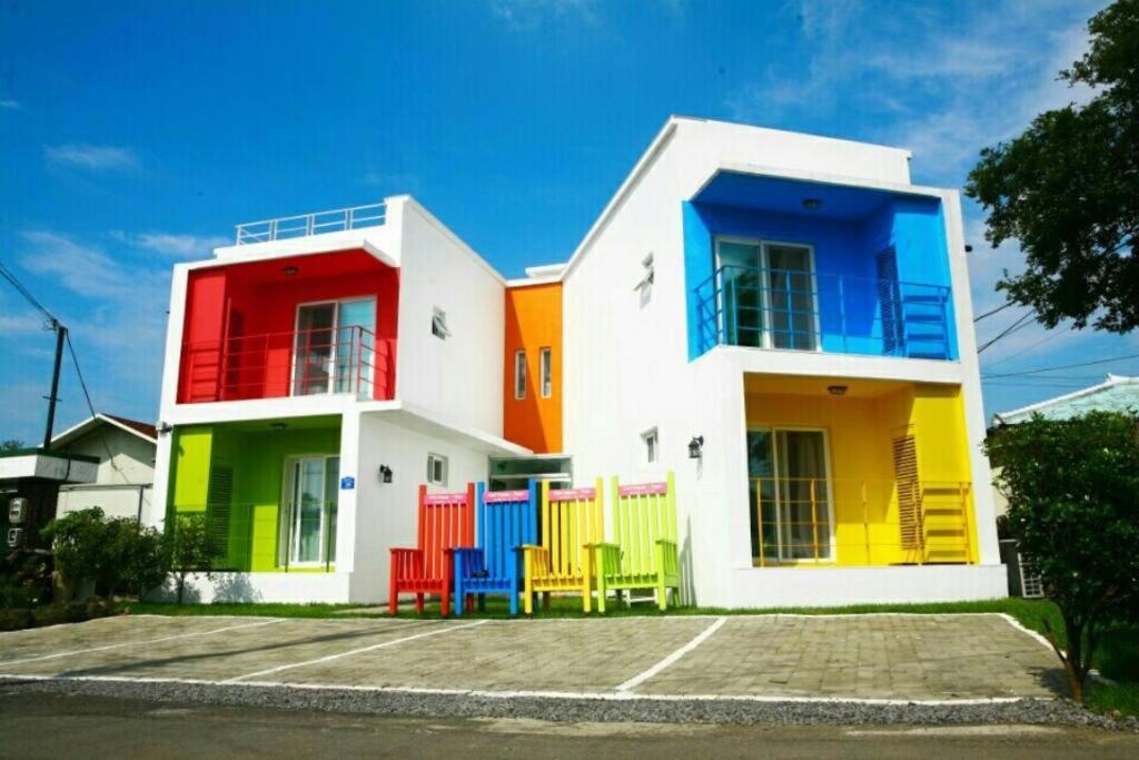 une maison colorée avec des chaises colorées devant elle dans l'établissement Cozy House & Tour, à Jeju