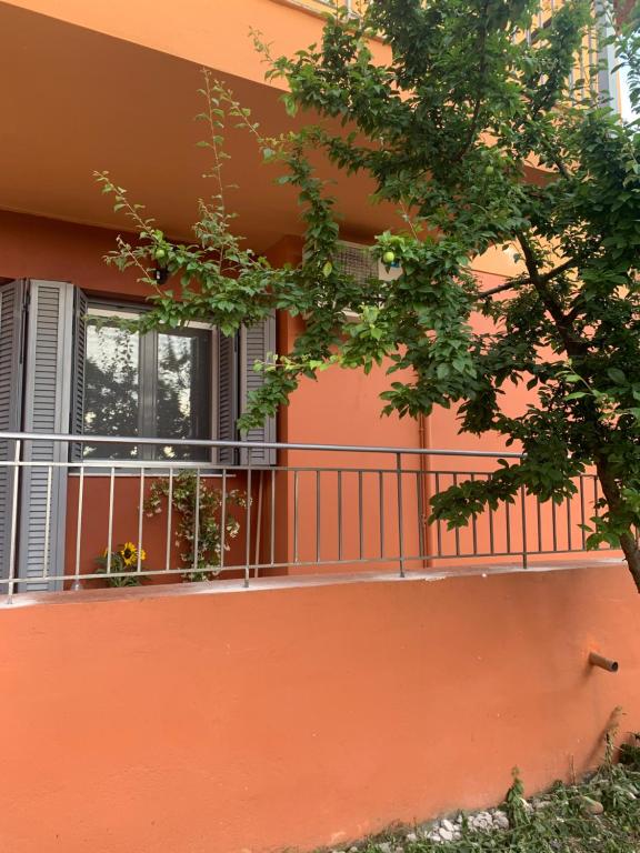un edificio de color naranja con balcón y un árbol en Lefkas Apartment, en Lefkada