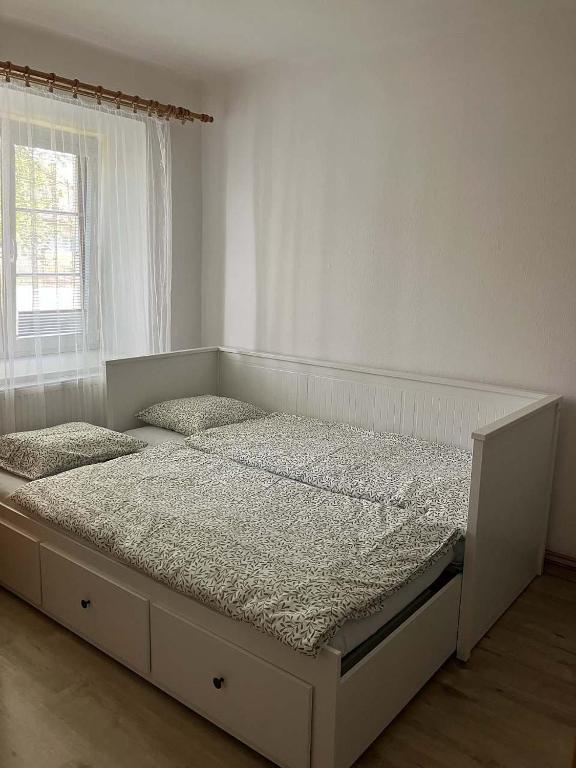 un letto bianco in una stanza con finestra di Chaloupka a Příbraz