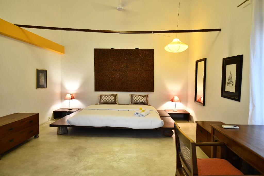 a bedroom with a bed and two tables and two lamps at La Closerie - Bay of Bengal in Puducherry