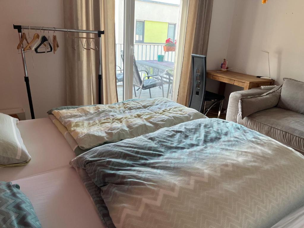 a room with two beds and a couch and a window at Schönes Zimmer in zentraler Lage in Ulm