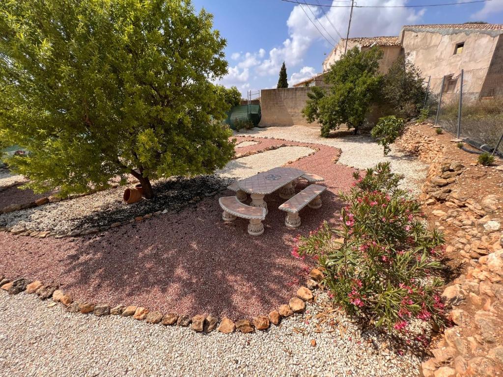 a picnic table and a tree in a garden at Casa Amor - Casa Esmeralda - 3 Bedroom Apartment with Shared Pool & Jacuzzi Close to Parque Regional Sierra del Carche, hiking trails & striking views in Raspay