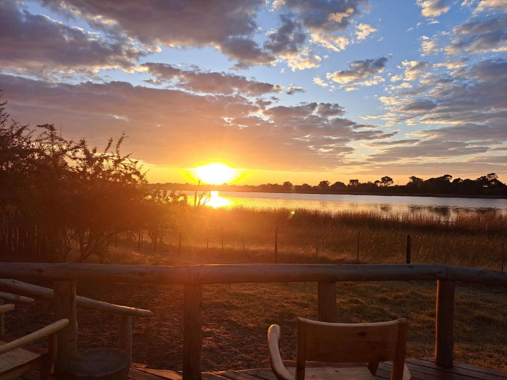 a sunset over a body of water with a bench at Semowi Lodge and Campsites in Mirapene