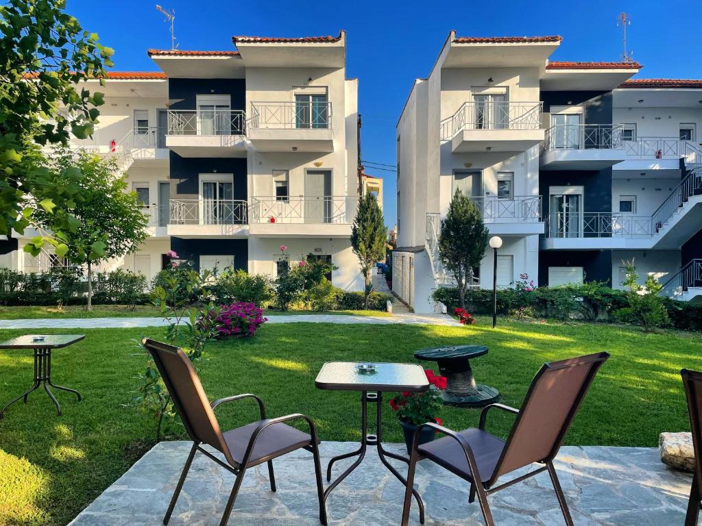 un patio avec des chaises et des tables en face d'un bâtiment dans l'établissement DOMES APARTMENTS, à Kallithéa Halkidikis