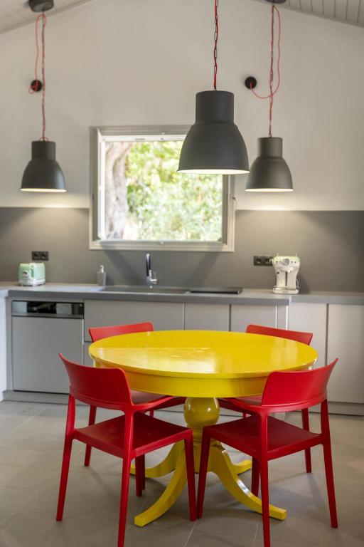 a kitchen with a yellow table and four red chairs at Paleokastritsa Red Gate Flat in Paleokastritsa